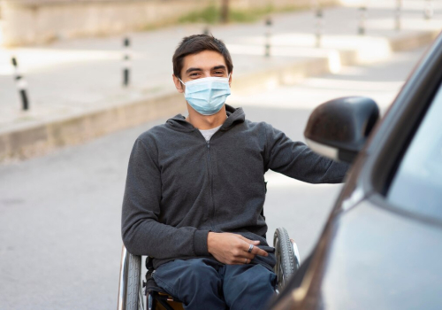 Man in wheelchair getting into car with NDIS Travel Transport Assistance.