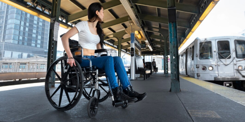 Woman in wheelchair at train station using NDIS Travel Support Services.