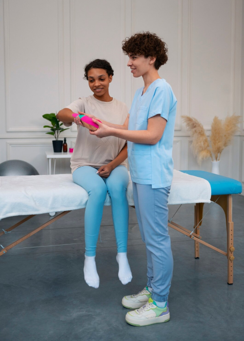 NDIS physiotherapist guiding patient with resistance band therapy in clinic.